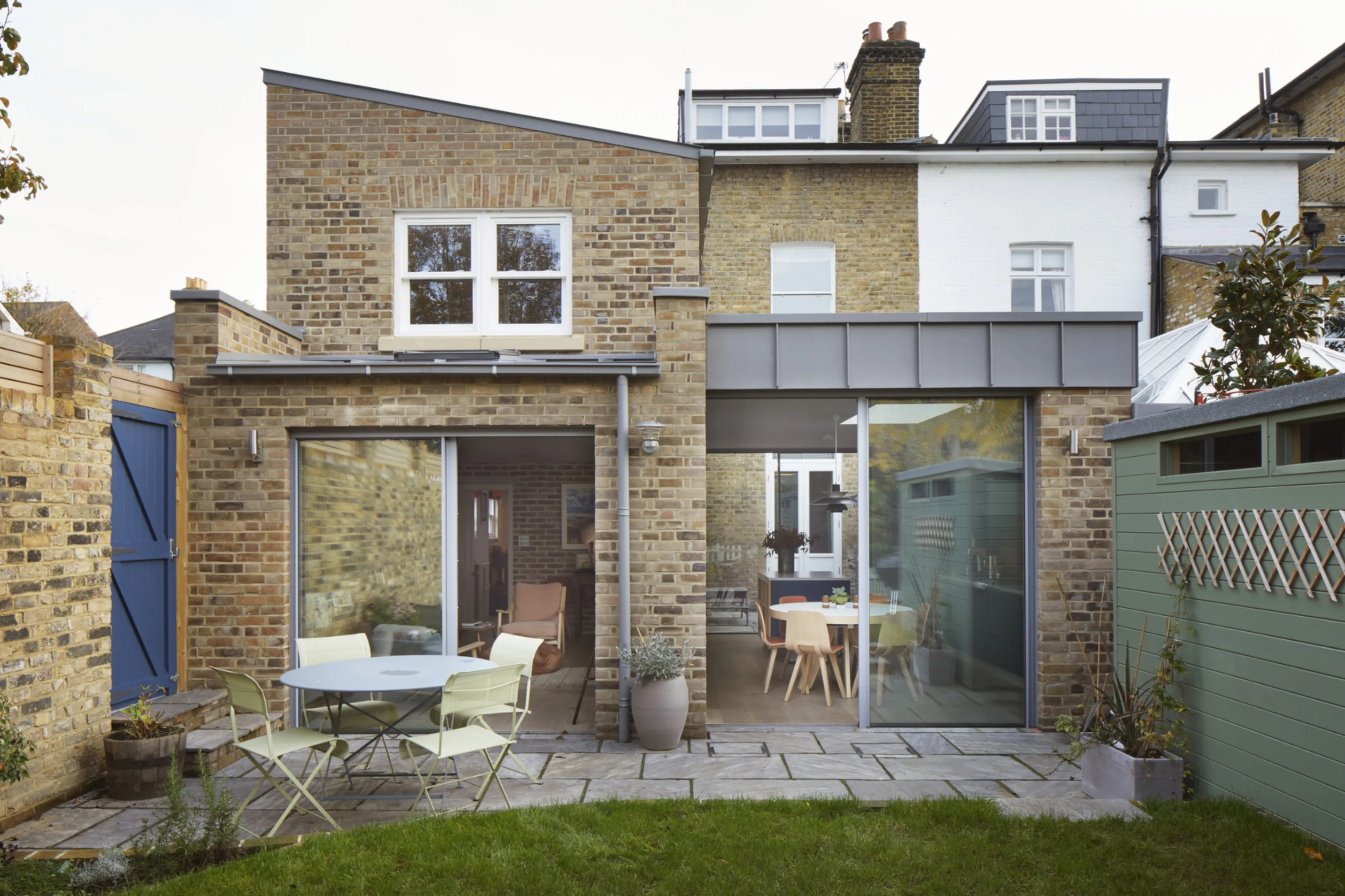 Rear garden view of contemporary brick extensions with large sliding doors and landscaped outdoor space.
