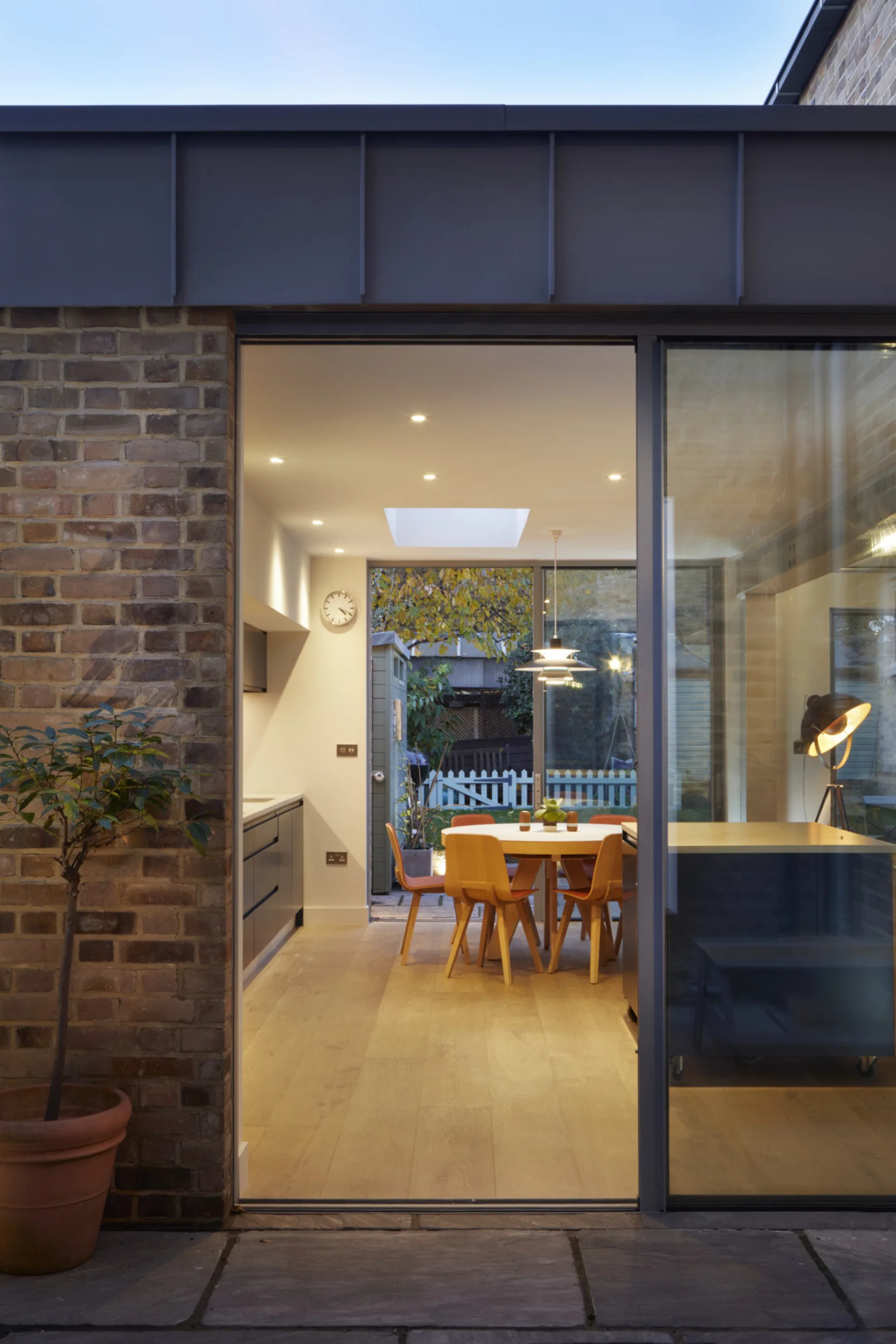 Evening view through sliding glazed doors into the kitchen extension, illuminated by rooflights and warm interior lighting