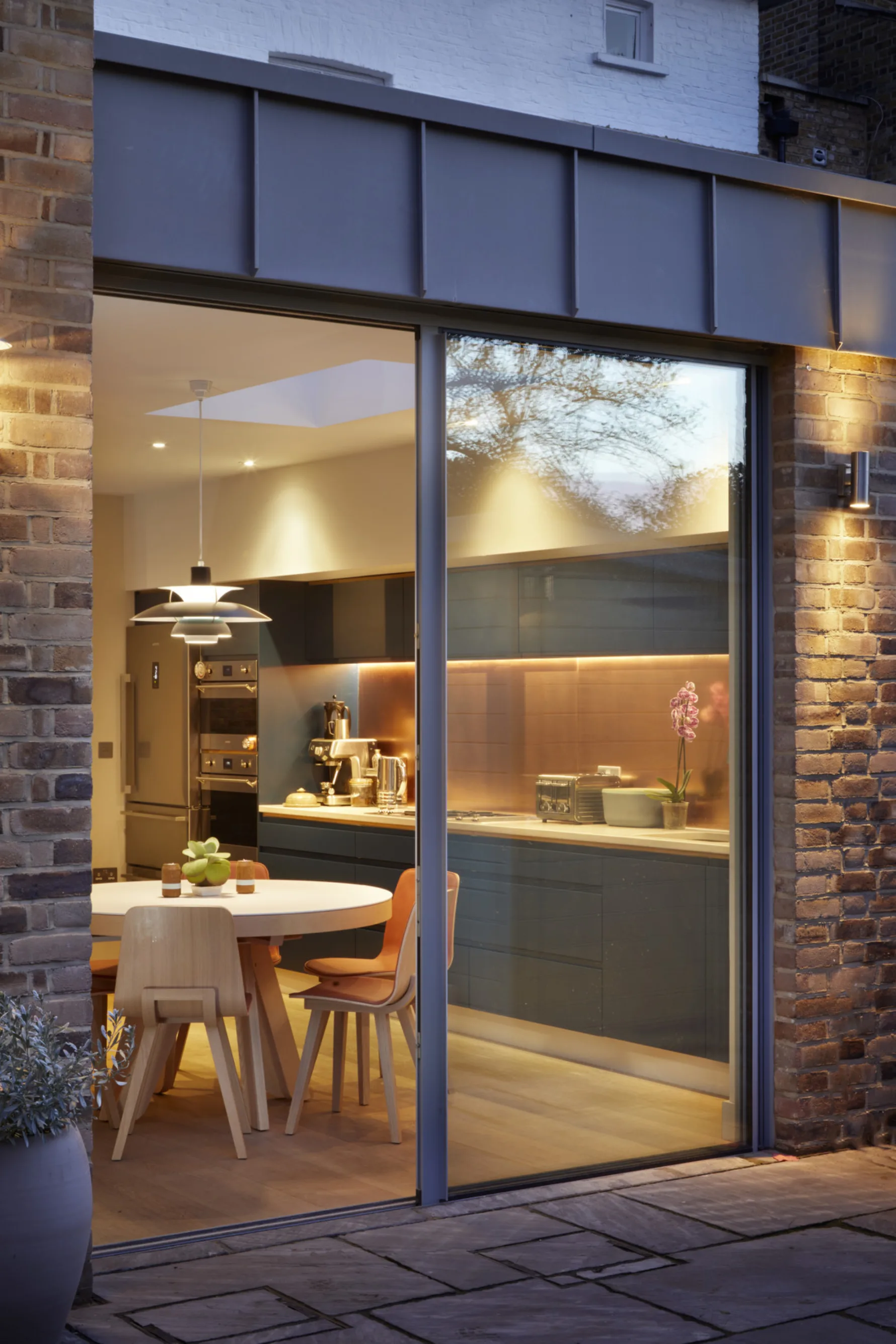 Evening view into the kitchen extension highlighting warm interior lighting and generous glazing.