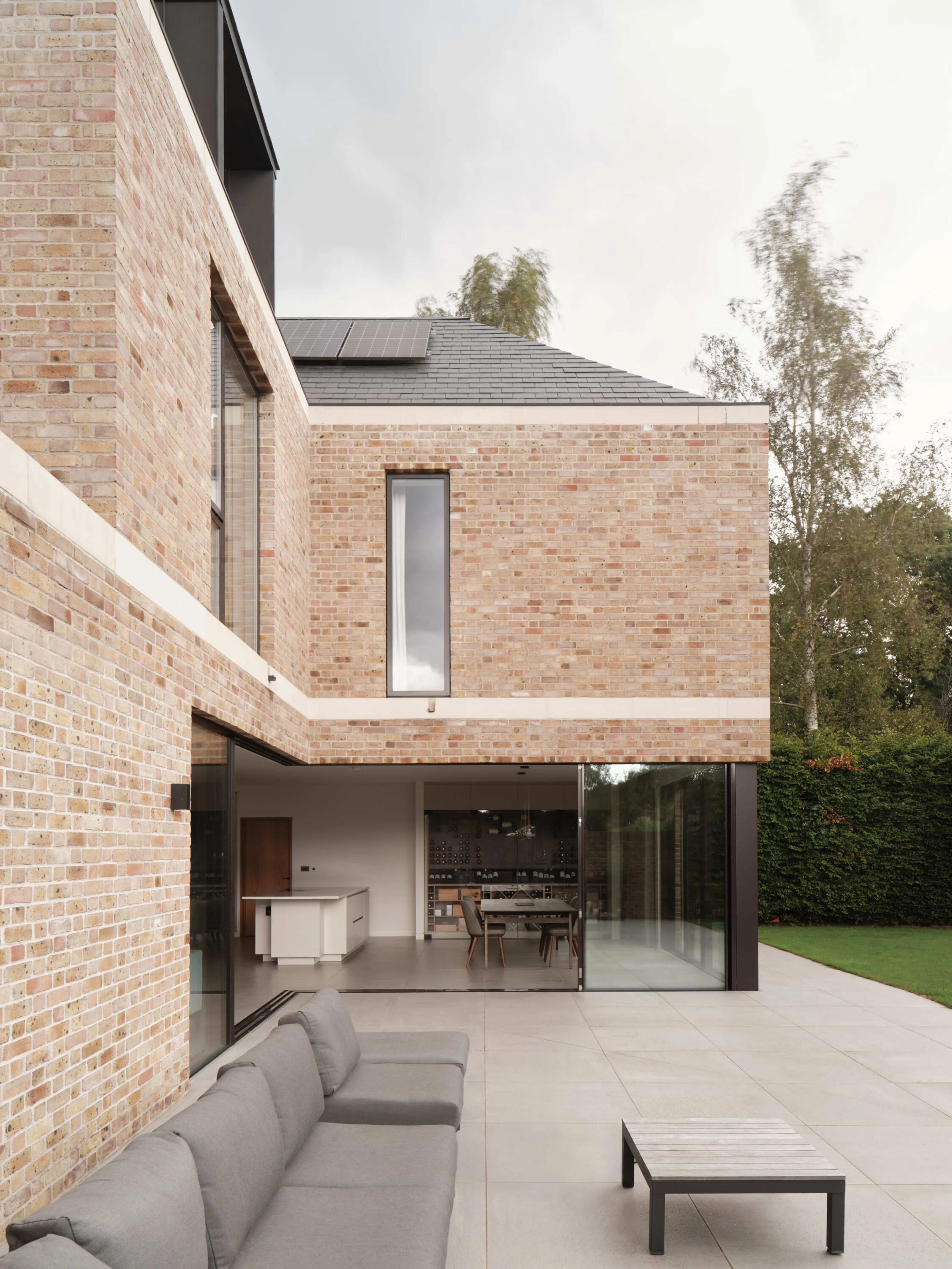 Flemish bond brick exterior with large sliding glass doors opening onto a stone terrace
