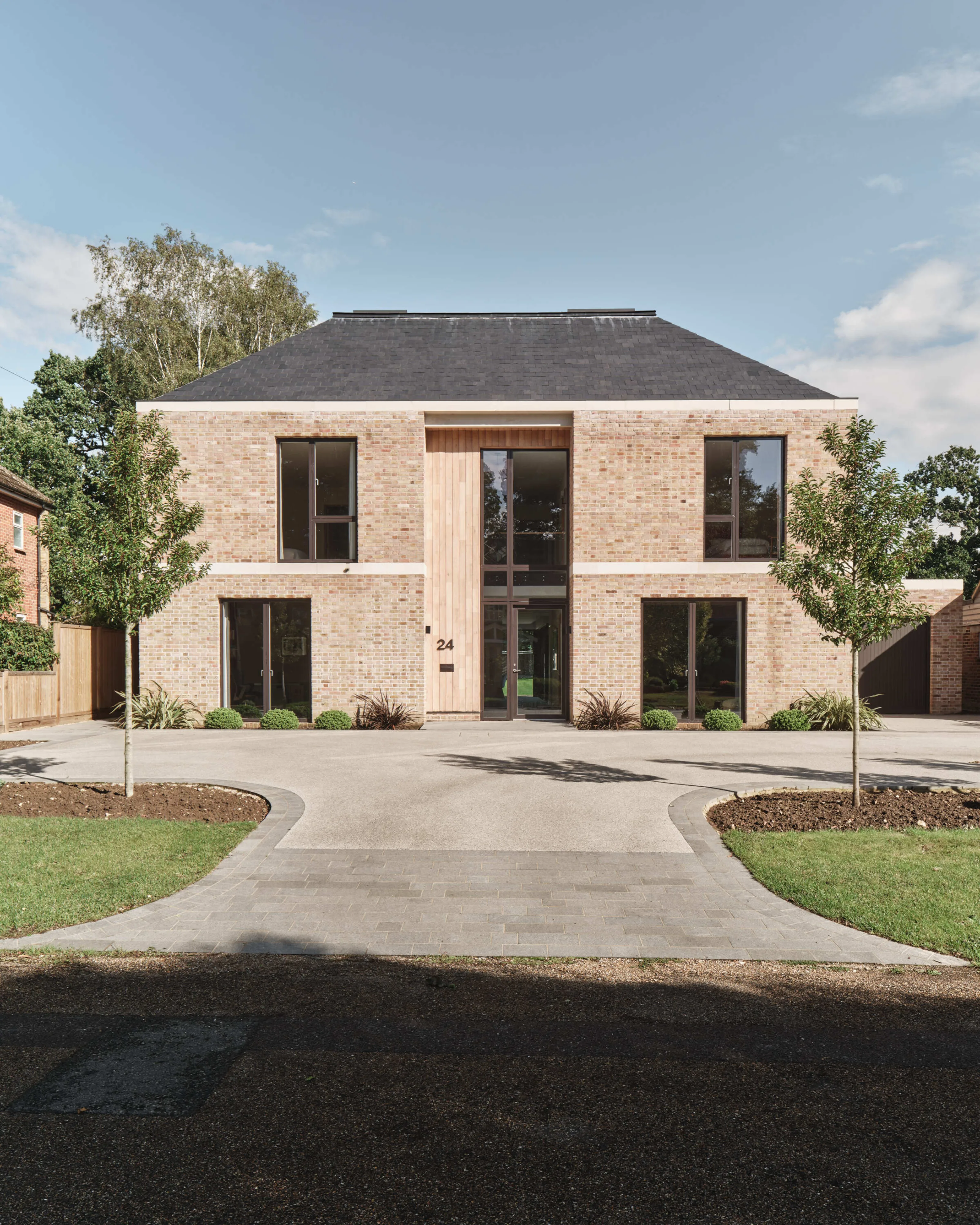 New-build luxury home with minimalist brick facade and driveway leading to entrance