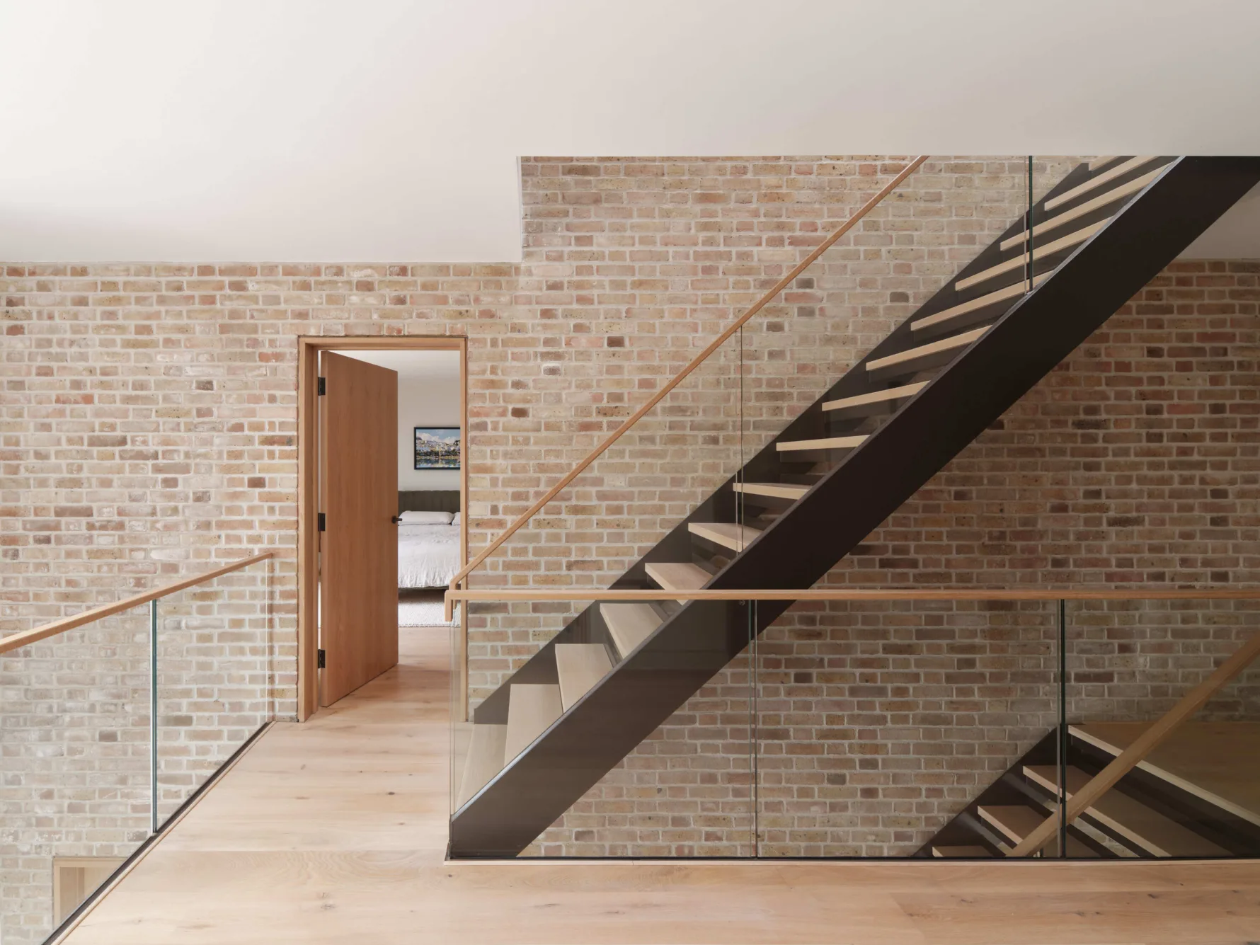 Contemporary interior staircase with exposed brick wall and open-plan modern design.