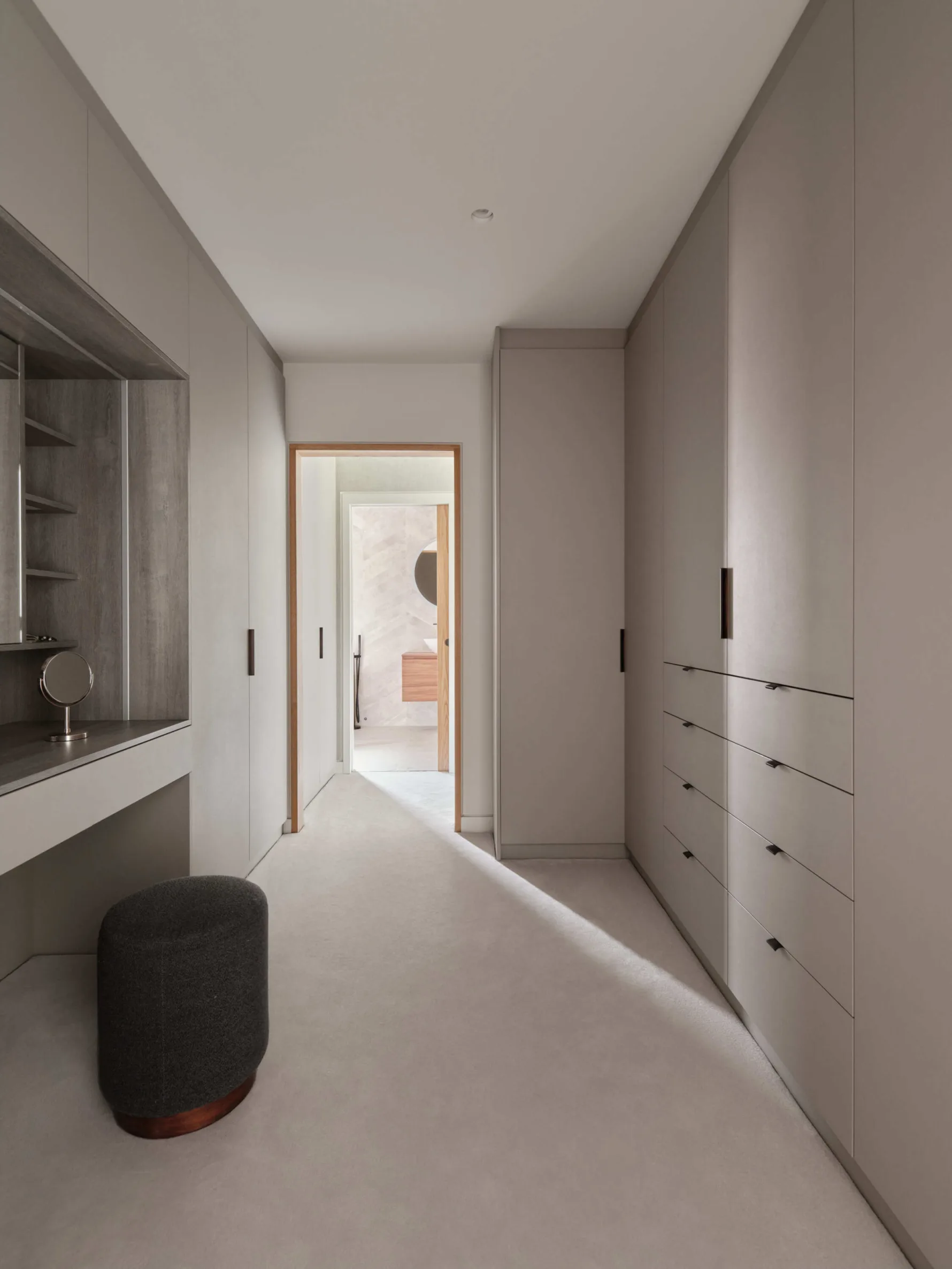 Modern minimalist dressing room with built-in wardrobes, neutral tones, and a vanity area
