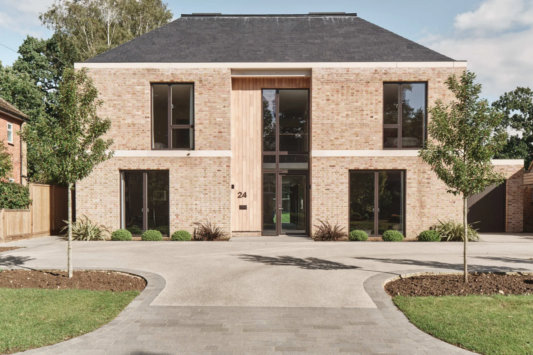 New-build luxury home with minimalist brick facade and driveway leading to entrance