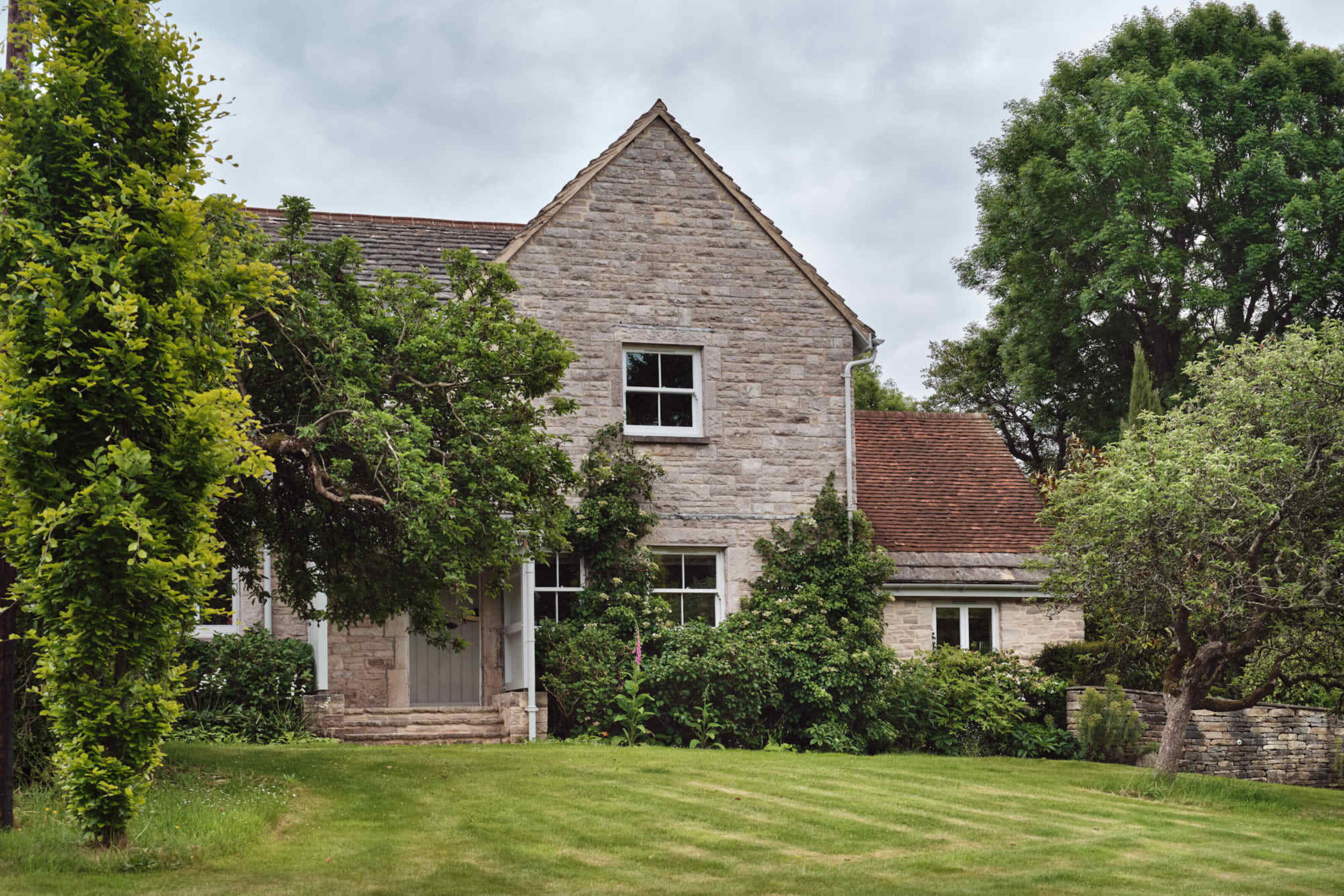Garden elevation of Corfe Castle House showing the restored stone façade, climbing plants and mature garden setting.