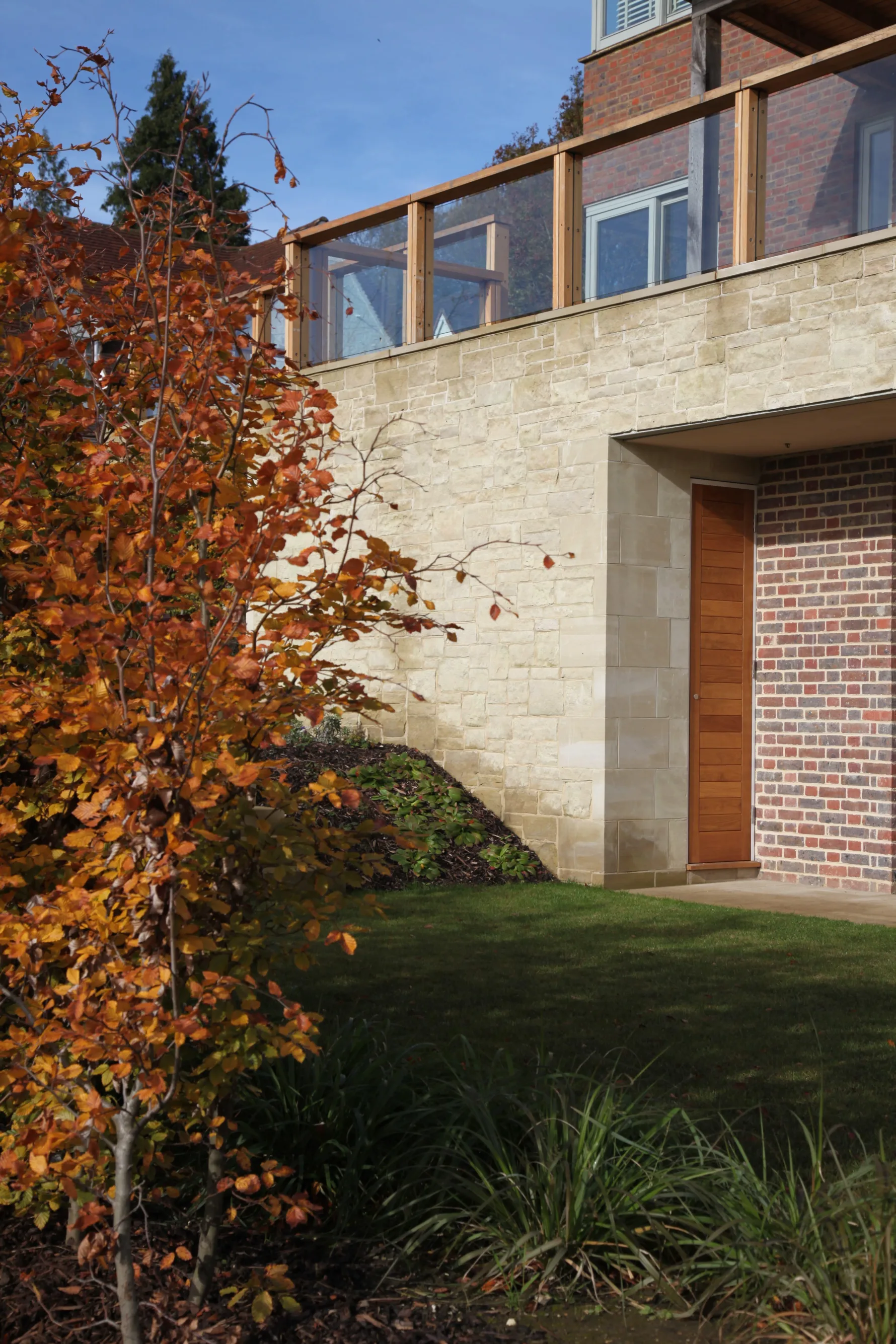 Landscaped garden and stone retaining wall beneath the elevated terrace of Guildford House.