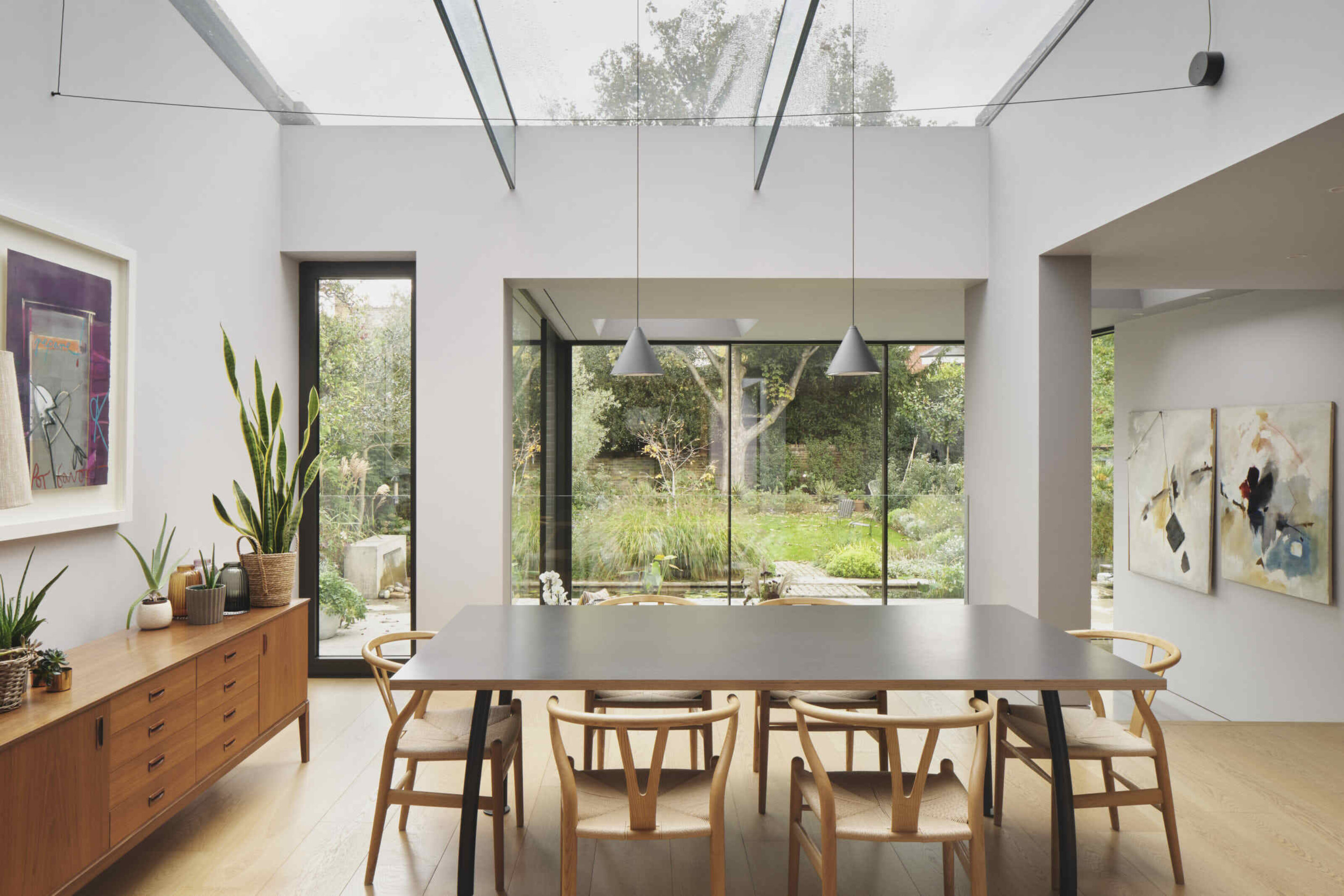 Dining area at Kew House beneath a bespoke structural glass roof, bringing natural daylight deep into the extension.