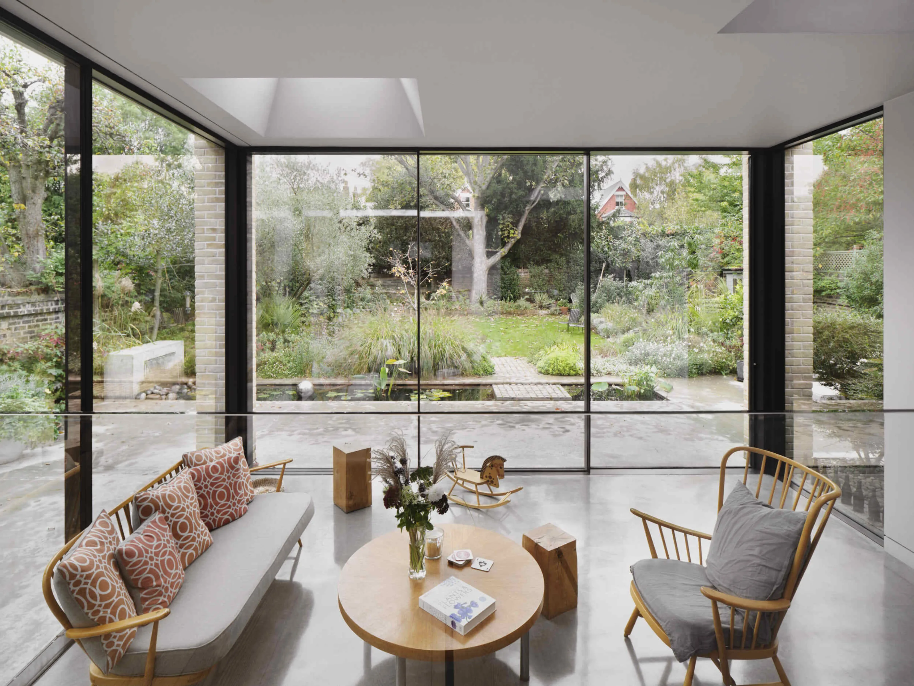 Garden room interior at Kew House with full-height glazing overlooking the landscaped rear garden and flooding the space with natural light