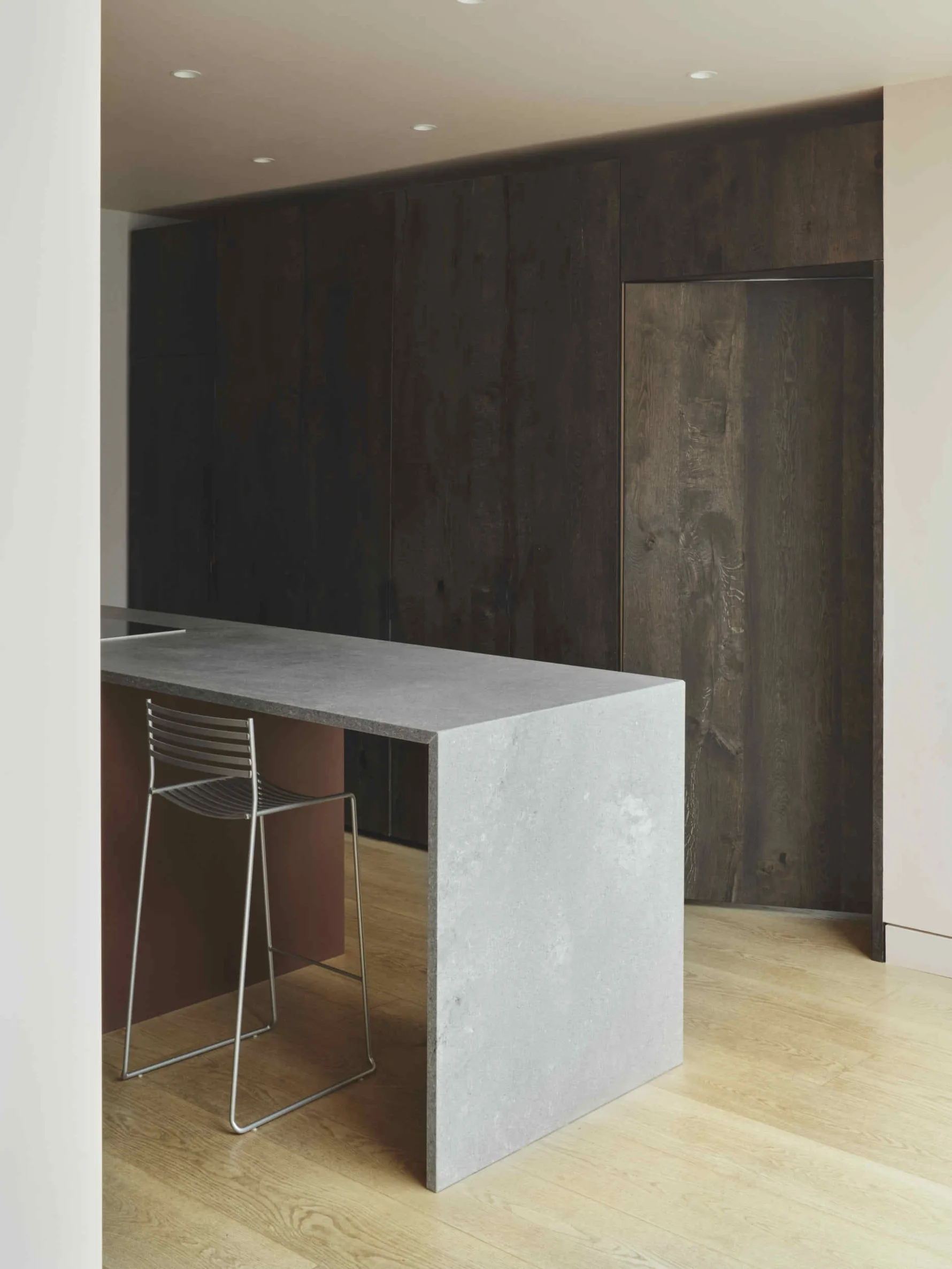 Bespoke kitchen island and dark timber cabinetry within the contemporary rear extension at Kew House.