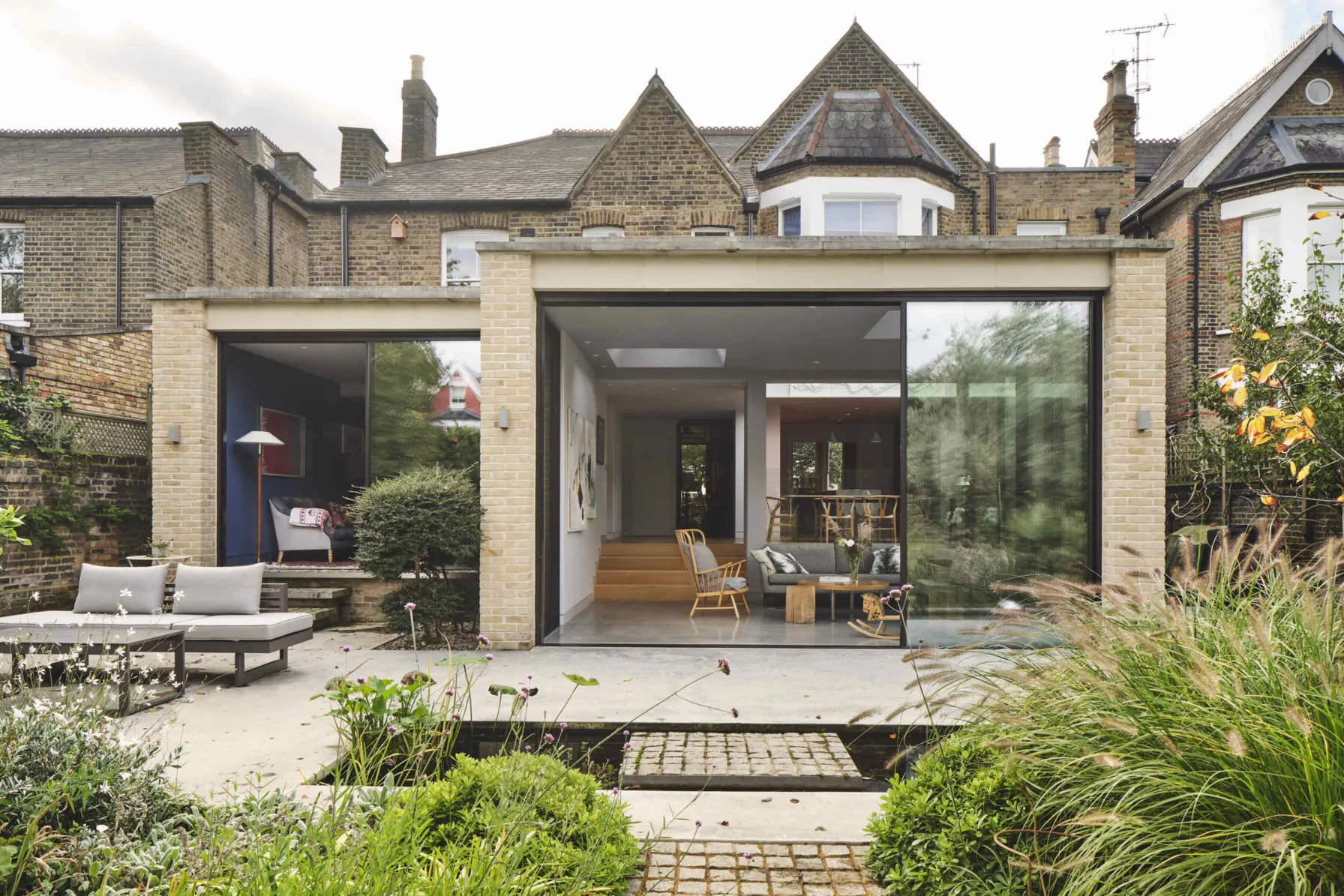 Rear elevation of Kew House showing a contemporary glazed pavilion extension opening onto a landscaped garden.