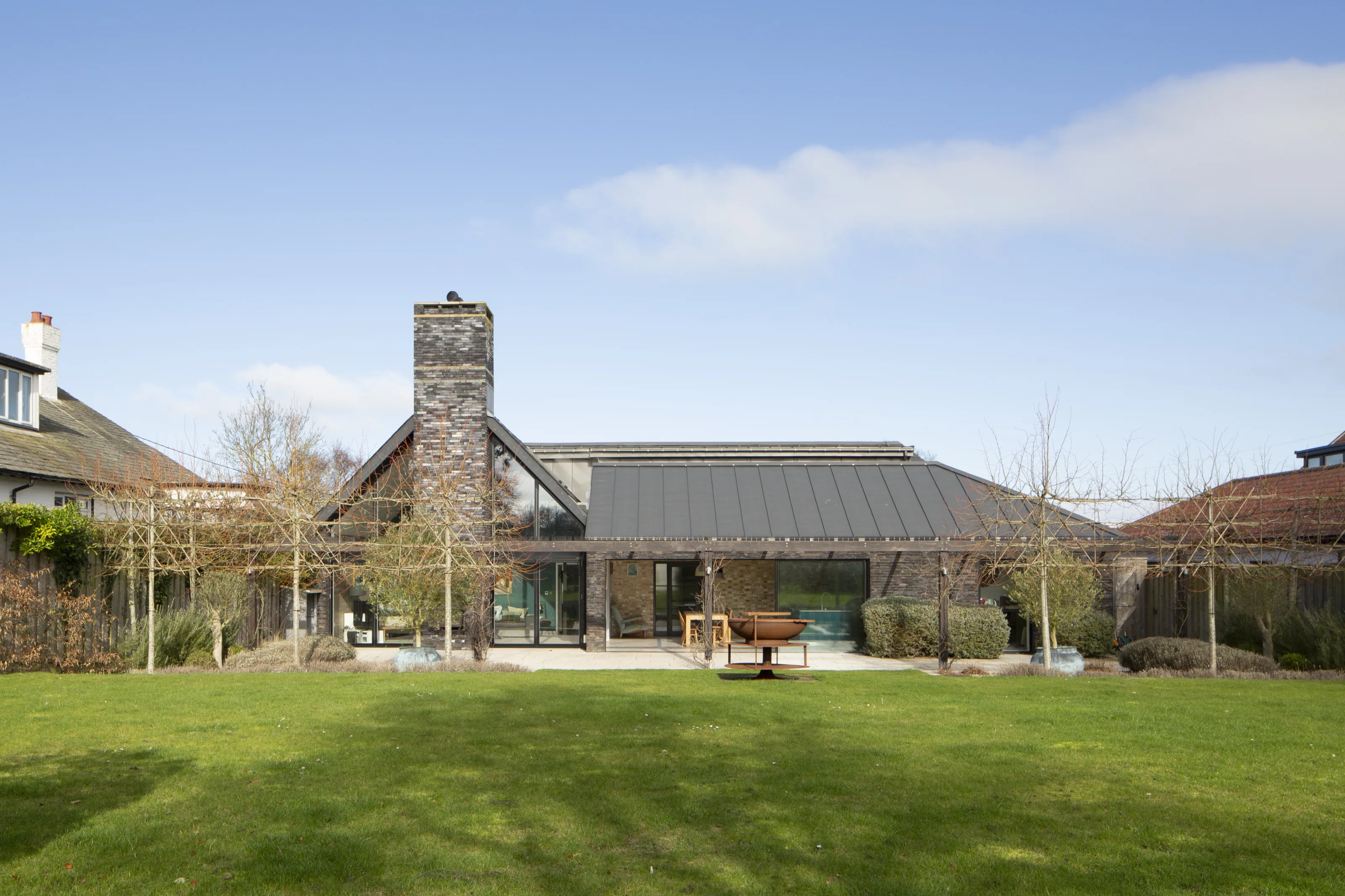 Rear elevation of contemporary house with zinc roof, chimney and garden lawn in Old Hunstanton
