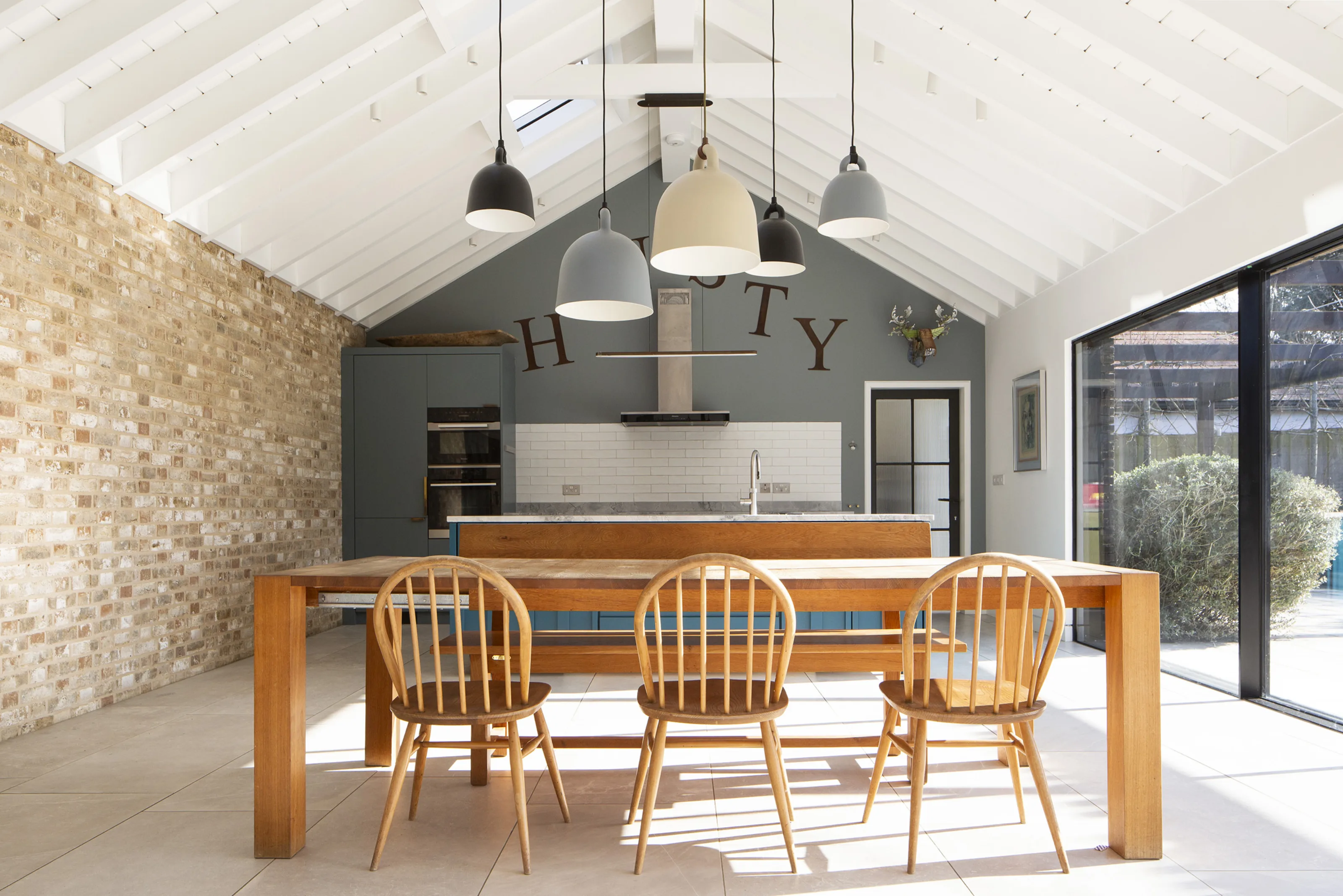 Open-plan kitchen with vaulted ceiling, island unit and brick wall in contemporary extension