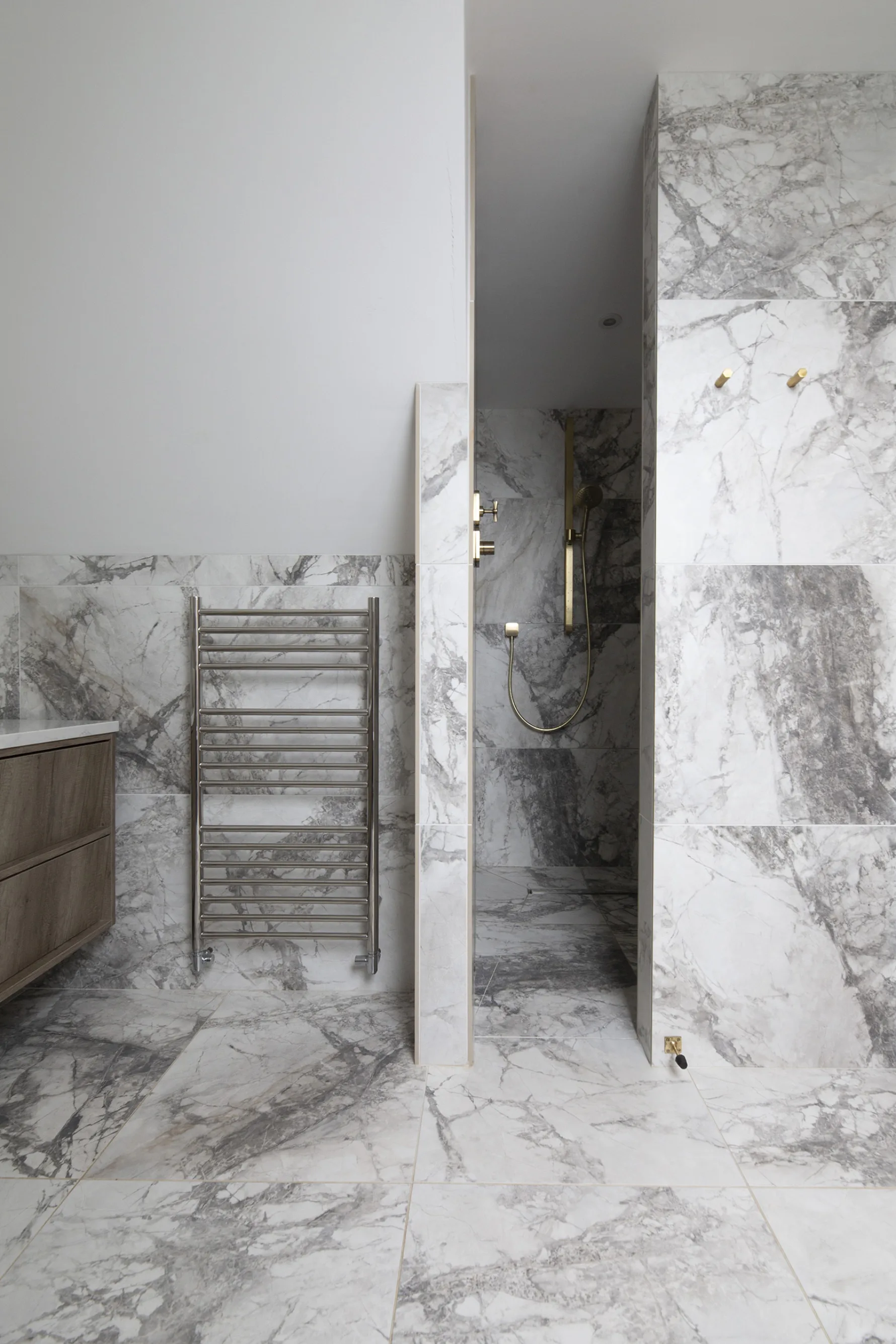 Walk-in shower with marble-effect wall tiles and brass fittings in contemporary bathroom renovation