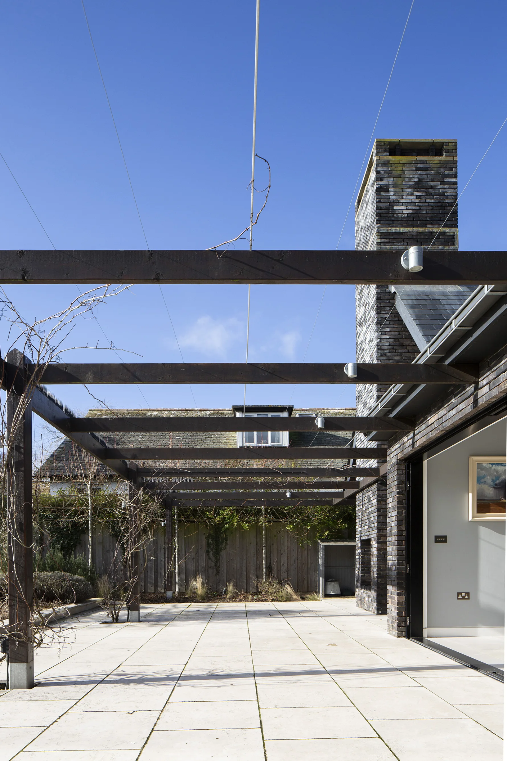 Timber pergola structure providing shading over terrace with climbing plants at contemporary house