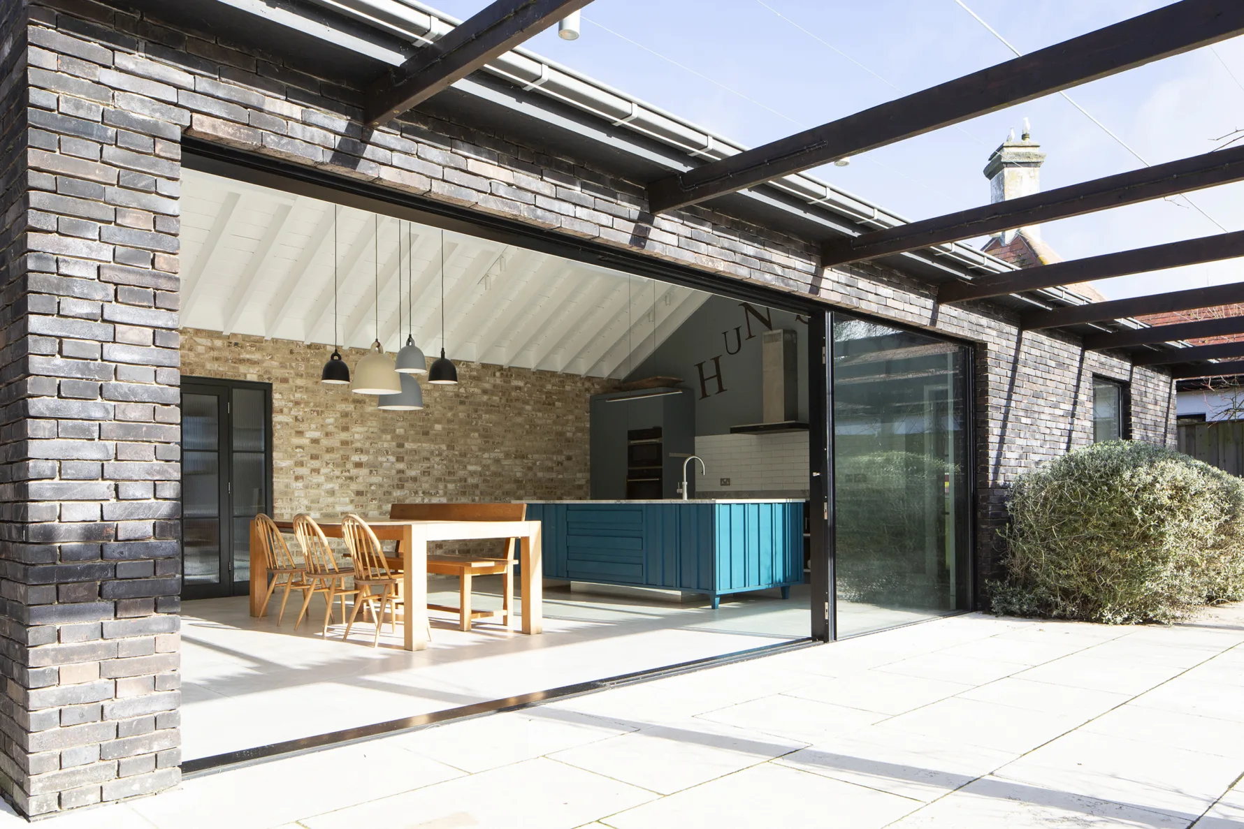 Open-plan kitchen and dining area with vaulted ceiling and large sliding doors opening to garden