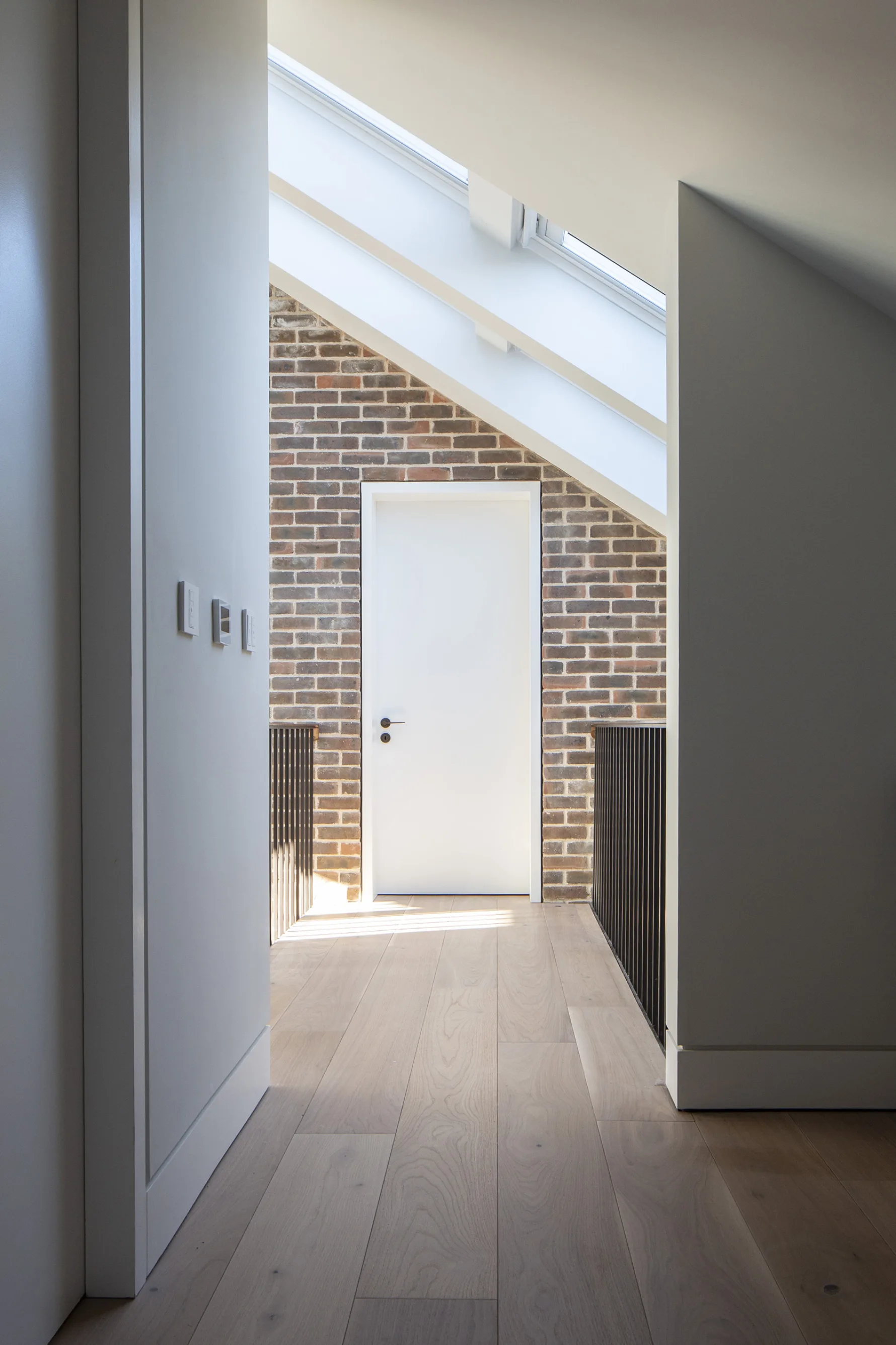 View down the hallway, wooden floor, exposed brickwork at the end and metal railings