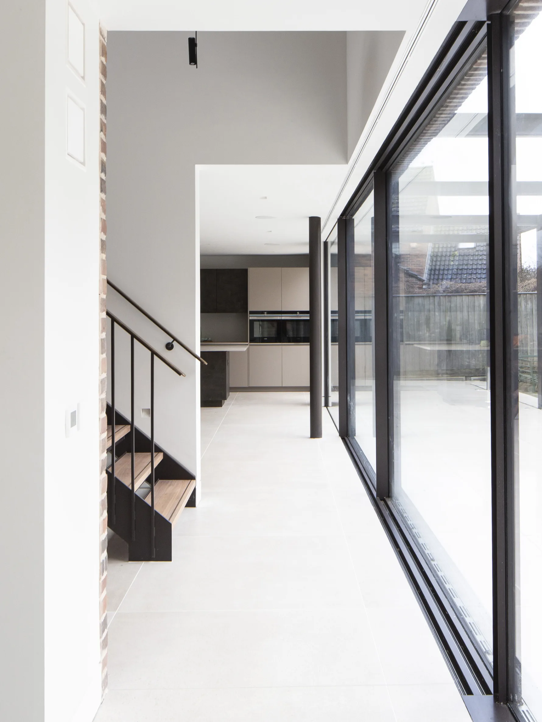 Modern open plan interior with floor-to-ceiling glazing, exposed brick wall and high ceiling in architect-designed home