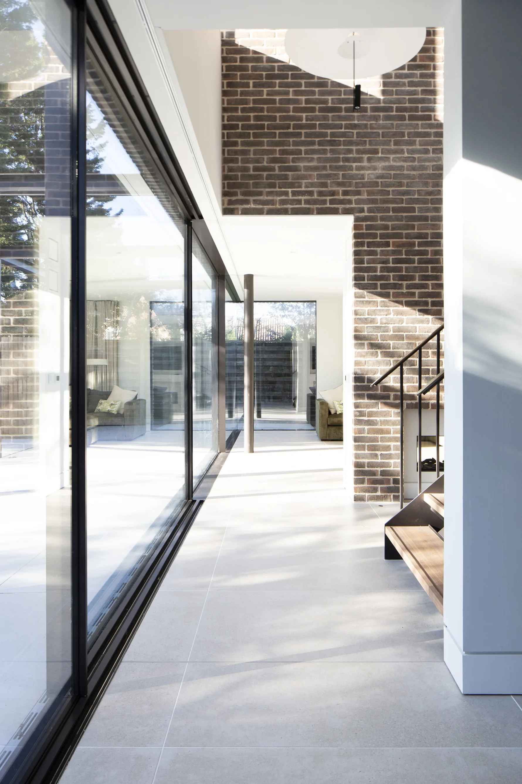 Contemporary open plan home with large sliding glass doors, minimalist stair and seamless indoor-outdoor connection