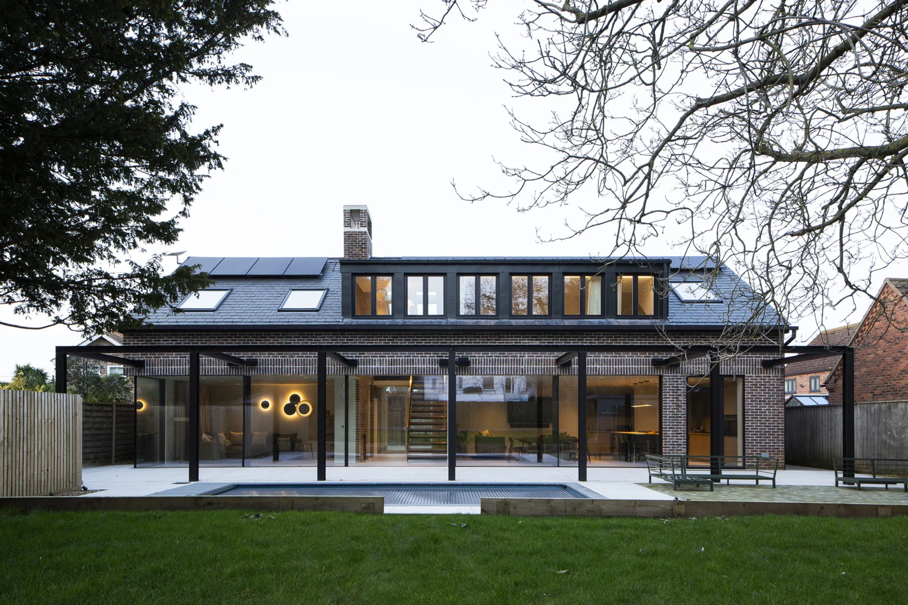 Contemporary brick house new build with large glass doors overlooking a landscaped garden and patio