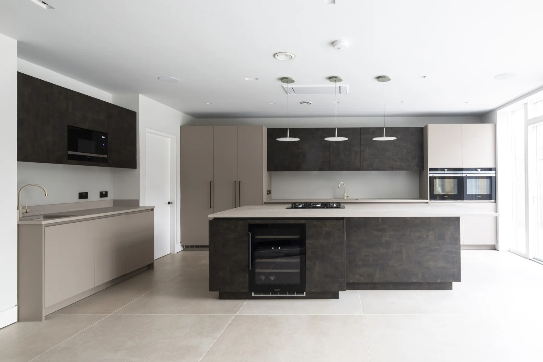 Contemporary kitchen with island, handleless units and integrated appliances in architect-designed UK home