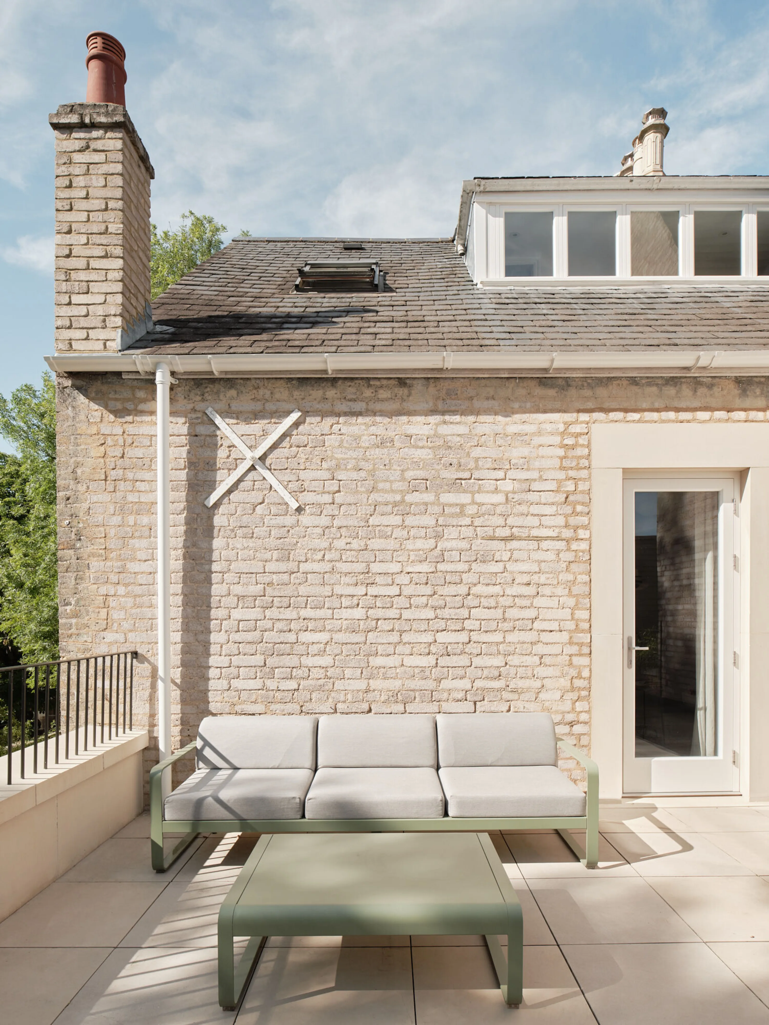Roof terrace with outdoor seating adjacent to a brick dormer extension on the upper floor of the renovated house.
