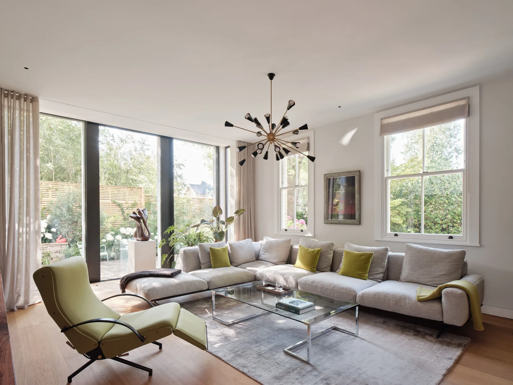Contemporary living room with large glazed doors opening onto the garden, featuring a sectional sofa and abundant natural light.