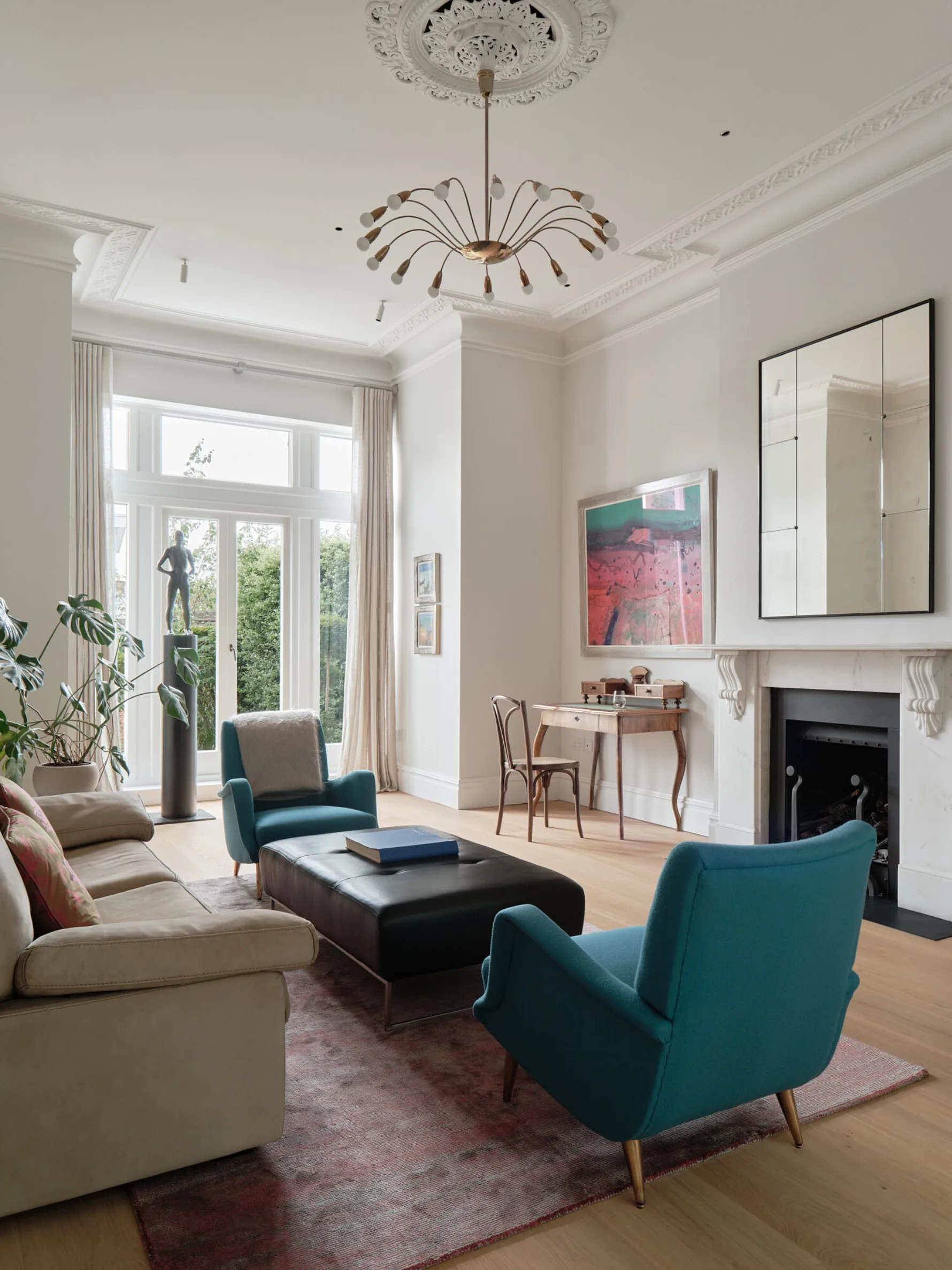 Reception room with restored decorative cornicing, marble fireplace, contemporary furnishings and tall glazed doors overlooking the garden.