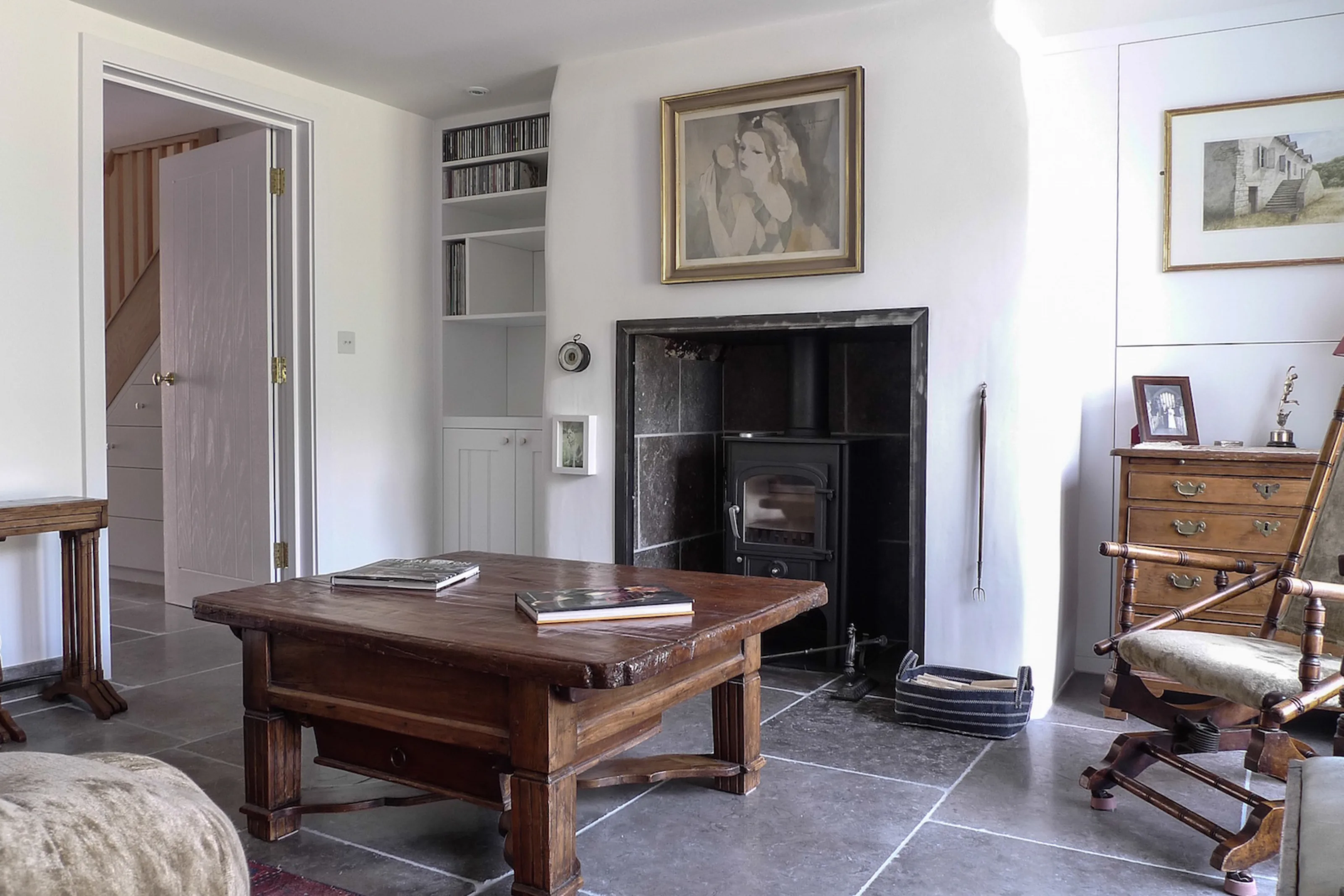 Living room at Thames Ditton House 04 combining traditional furnishings with natural materials and contemporary refurbishment, featuring a wood-burning stove, built-in joinery and natural stone flooring.