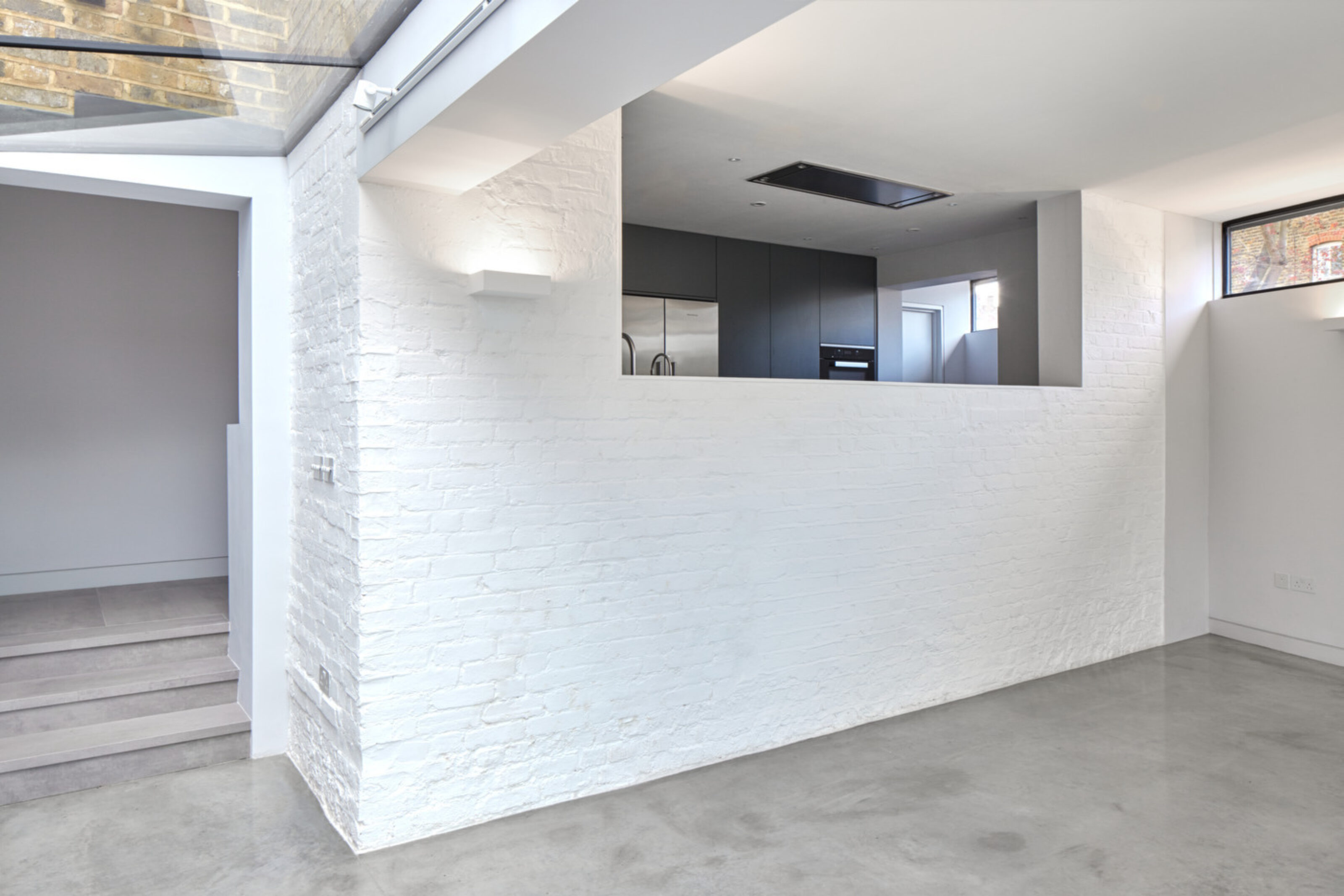 Open-plan living space at Twickenham House featuring exposed brickwork, polished concrete flooring and a contemporary rear extension.