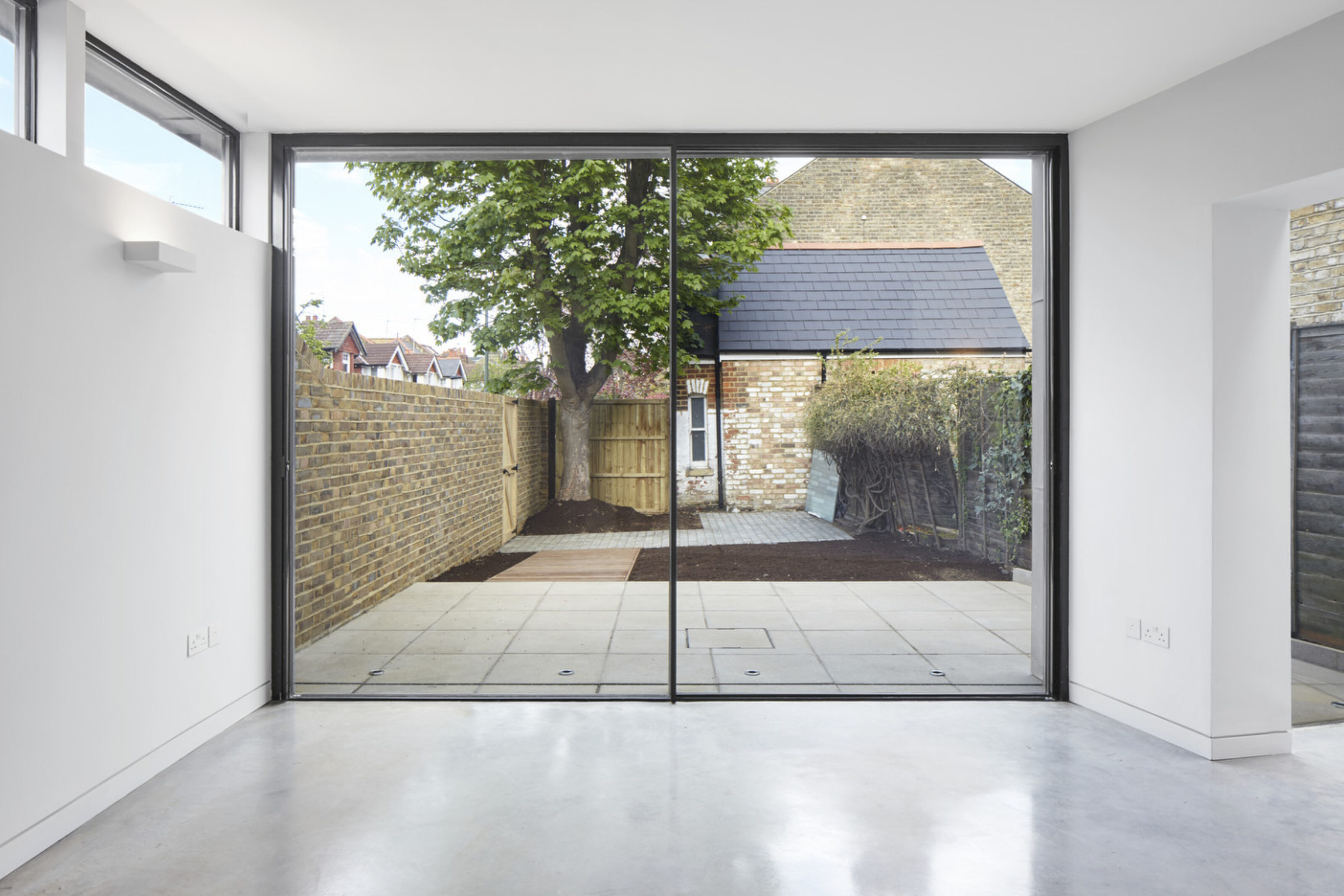 Large sliding glass doors at Twickenham House connecting the open-plan extension to a landscaped rear garden.