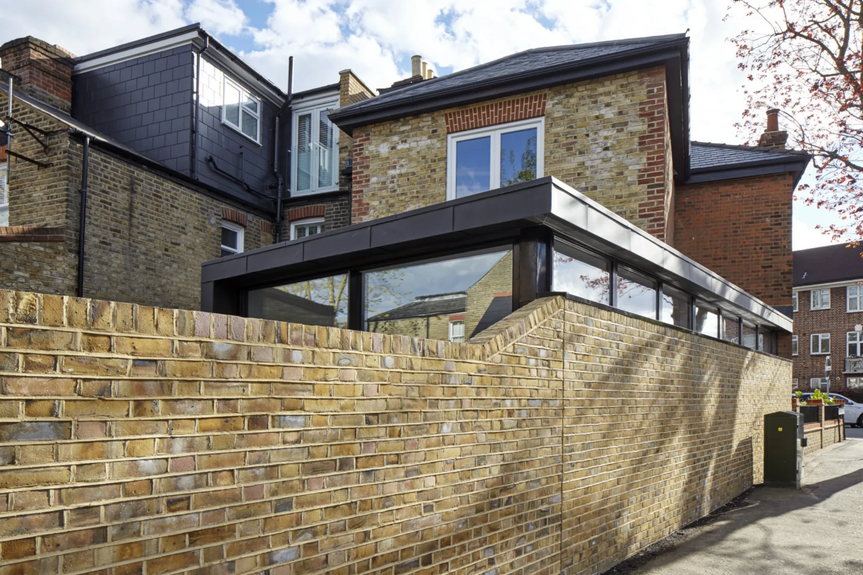 Contemporary rear extension at Twickenham House with zinc-clad façade, horizontal glazing and landscaped boundary walls.
