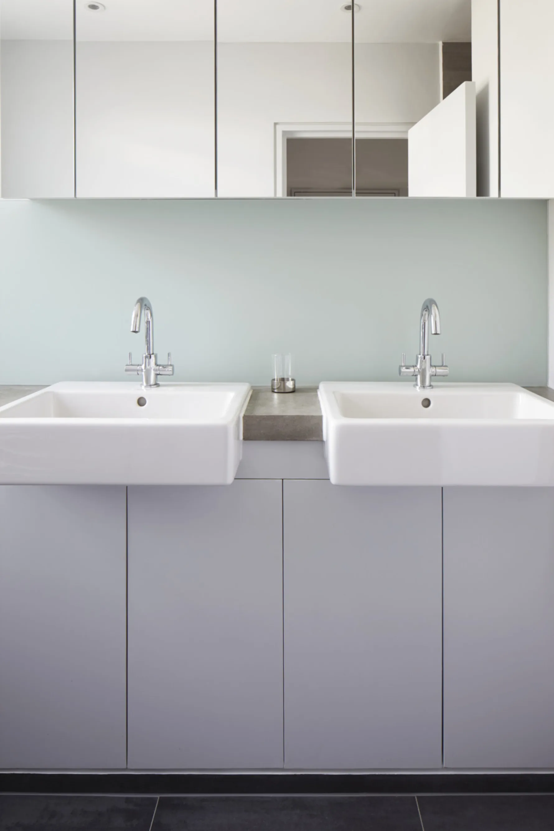 Contemporary bathroom at Twickenham House with twin vanity basins, mirrored storage cabinets and minimalist finishes.