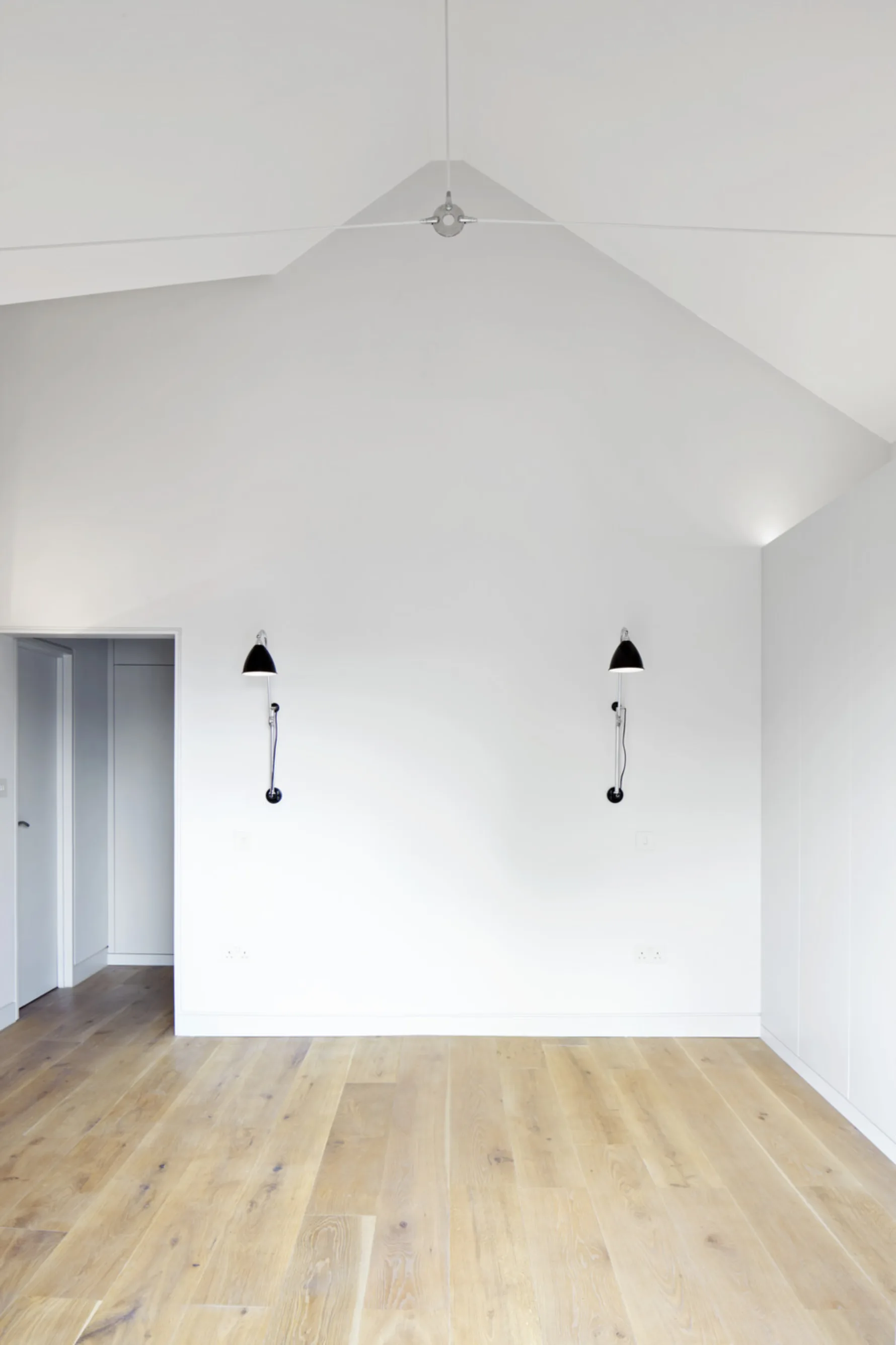 Bright principal bedroom at Twickenham House with vaulted ceiling, oak flooring and built-in wardrobes.