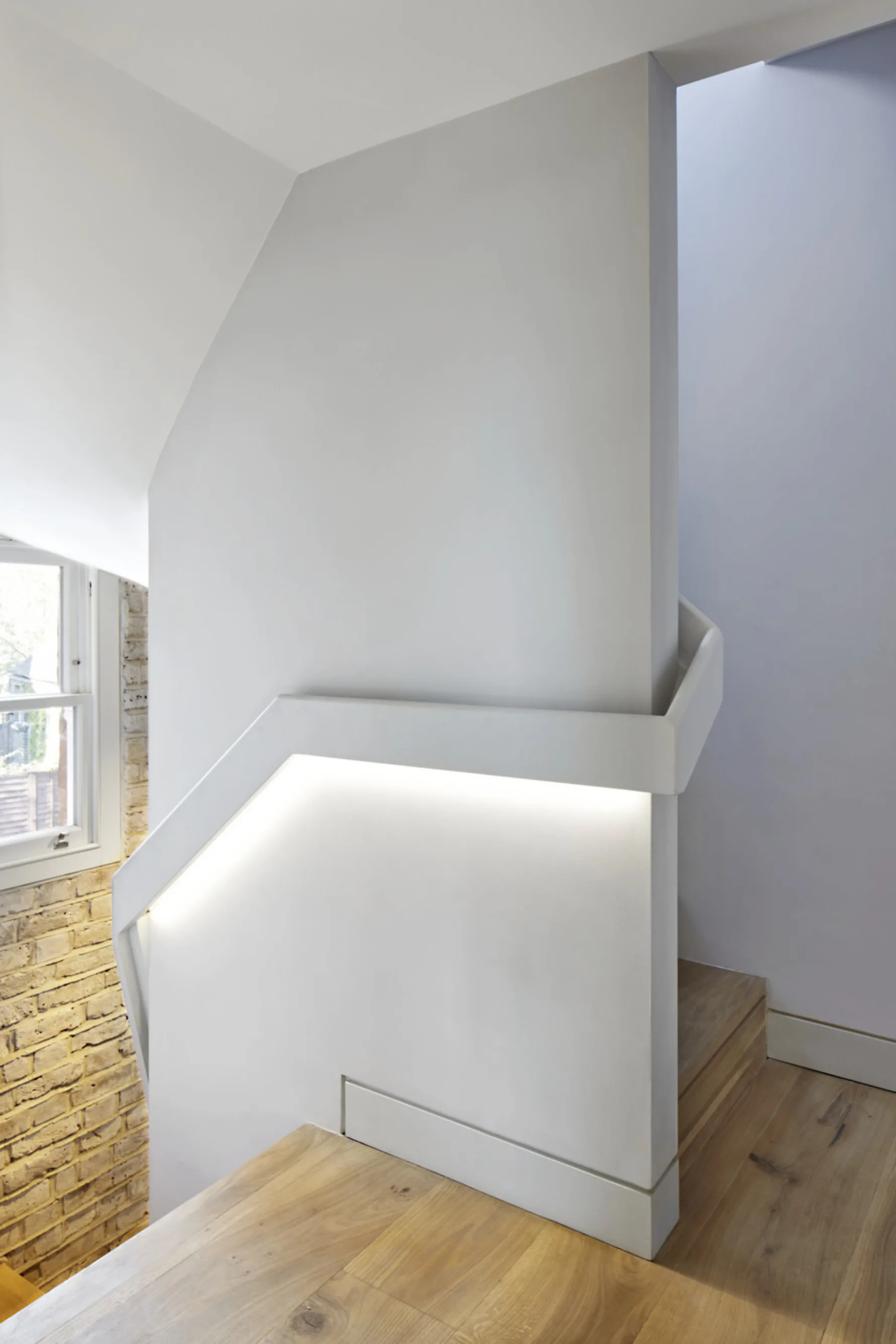 Contemporary staircase landing at Twickenham House featuring oak flooring, integrated lighting and clean architectural detailing.
