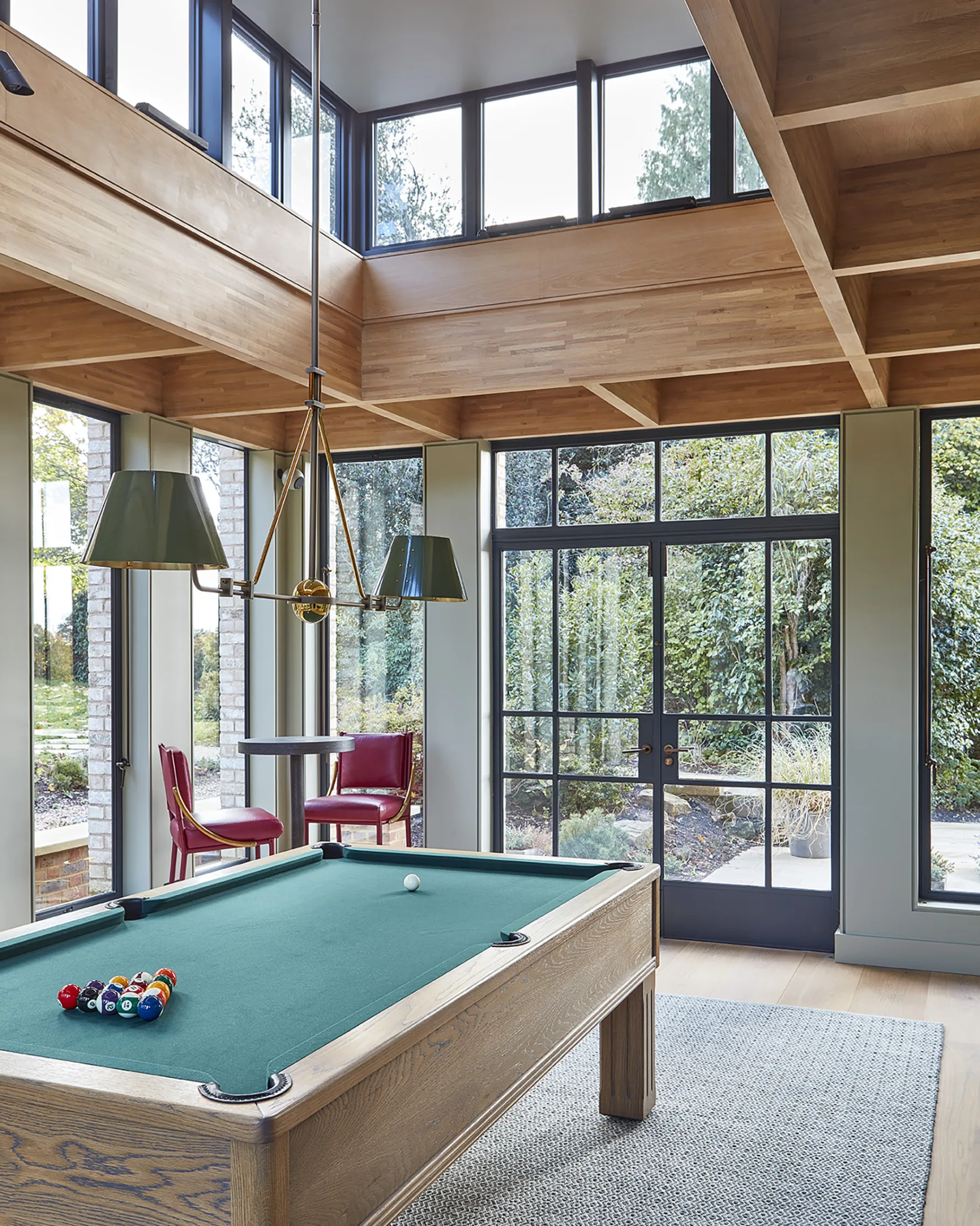 Games room at Westerham House featuring a double-height oak-lined interior, steel-framed glazing and views of the landscaped gardens.